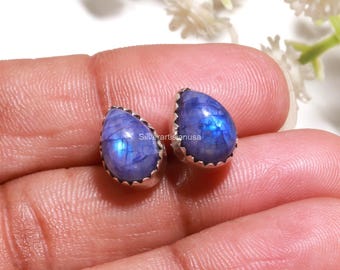 Op de afbeelding: Een paar druppelvormige oorknopjes met iriserende blauwe maanstenen in geschulpte zilveren zettingen. De stenen vertonen een duidelijke blauwe adularescentie en interne breuklijnen, met de tekst silverartisanusa zichtbaar tussen de stenen.