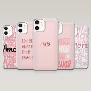 Op de afbeelding: Vijf roze telefoonhoesjes met verschillende ontwerpen. Eén hoesje heeft het woord "Amore" in rood schrift. Een andere heeft "More Amor Por Favor" in rood. De andere hoesjes hebben de woorden "Amo", "More Love" en "More" in roze.