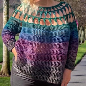 May include: A handmade, rainbow-colored crochet sweater. The sweater transitions from green at the top to blue, purple, and finally gray at the bottom. The neckline and upper chest feature an open, cut-out design. The sleeves are long and the fit is loose.