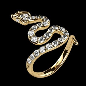 Könnte beinhalten: Ein goldfarbener Schlangenring mit funkelnden, klaren Edelsteinen. Der Ring hat die Form einer Schlange, mit dem Kopf oben und dem Schwanz, der sich um den Ringkörper wickelt. Die Edelsteine sind im Pavé-Stil gesetzt.