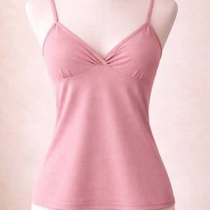 Op de afbeelding: Een stoffig roze camisole top met dunne spaghettibandjes en een V-hals. De top wordt getoond op een mannequin, waarbij de getailleerde silhouet en de geplooide details bij de buste worden benadrukt. De stof lijkt zacht en licht.