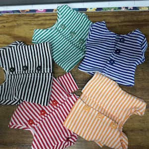 May include: Five striped shirts in different colors, including black and white, green and white, blue and white, red and white, and orange and white. Each shirt has a button closure down the front.