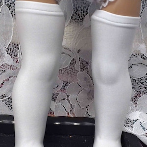 Puede incluir: Un par de medias blancas hasta la rodilla con un borde de encaje blanco en la parte superior.