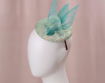 Fascinator astratto con bottoni a forma di uccello nei colori verde acqua e azzurro pastello.