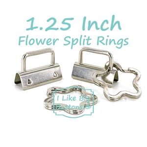 May include: Two silver-toned metal hardware clips with rectangular loops and two silver-toned flower-shaped split rings. The text 1.25 Inch Flower Split Rings and I Like Big Buttons is visible. The hardware has a smooth, metallic finish.