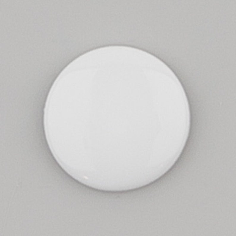 May include: A blank white round button, perfect for crafting or adding a personal touch to projects.
