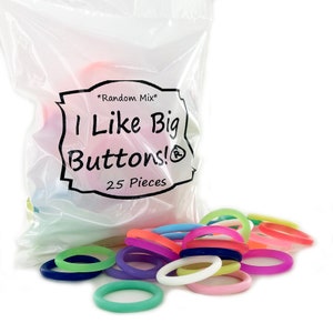 May include: A clear plastic bag filled with colorful, round silicone rings. The bag has a label that reads "*Random Mix* I Like Big Buttons! 25 Pieces". A pile of the rings are scattered in front of the bag, in shades of blue, green, pink, orange, and purple.
