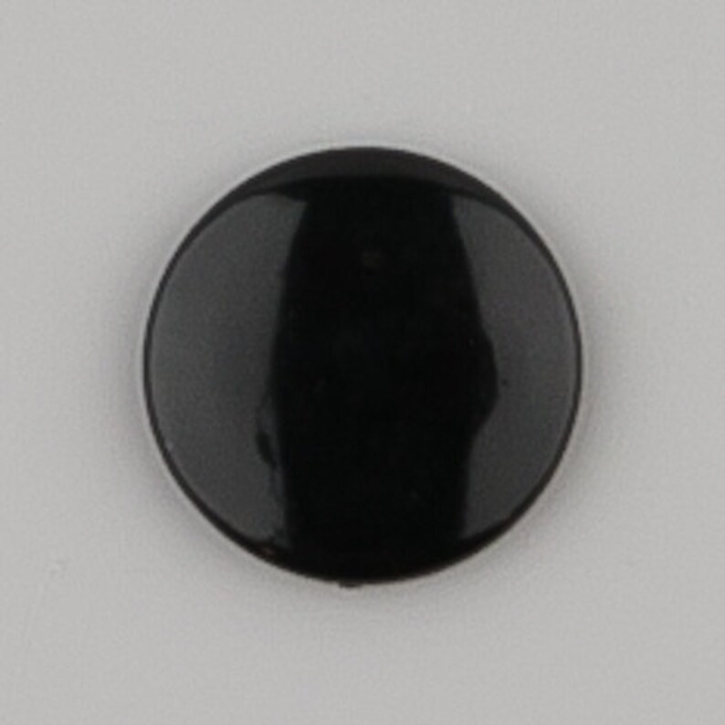 May include: A black round button with a glossy finish.