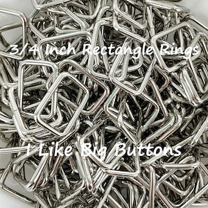 May include: A pile of shiny, silver 3/4 inch rectangle rings. The text "3/4 inch Rectangle Rings" and "I Like Big Buttons" are visible in the image. These metal rings are likely used for crafting or bag making.
