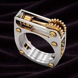 Può includere: Un anello argentato e dorato con un design meccanico. L'anello presenta un pistone, una biella e un ingranaggio, con dettagli dorati. L'anello ha una forma rettangolare con angoli arrotondati e viti dorate.