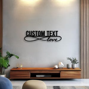 Op de afbeelding: Een zwart wandbord met de woorden CUSTOM TEXT in een vet, schreefloos lettertype boven het woord love in cursief schrift, waarbij beide tekstelementen zijn geïntegreerd in een doorlopende lus in de vorm van een oneindigheidsteken.