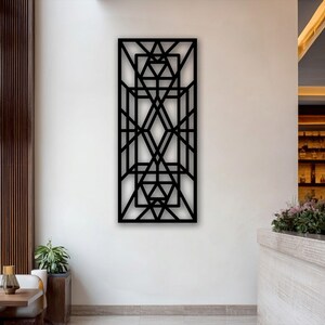 Puede incluir: Una pieza de arte mural rectangular de color negro con un complejo patrón geométrico de líneas, triángulos y formas de diamante que se cruzan. El diseño es simétrico, creando una cuadrícula estructurada de espacios abiertos y bordes.