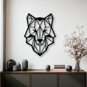 Op de afbeelding: Een zwarte wanddecoratie met een geometrisch ontwerp van een wolvenkop. Het stuk is samengesteld uit onderling verbonden rechte lijnen en hoekige vormen die het silhouet van een wolf vormen, wat een scherp, symmetrisch en lineair visueel patroon creëert.