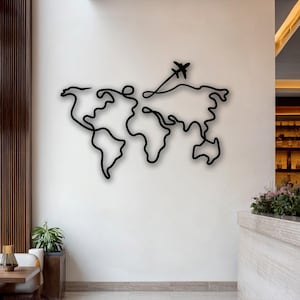 May include: A black metal wall art piece depicting a world map with a continuous line design. An airplane silhouette is shown taking off from the map. The artwork is mounted on a white wall, creating a modern and minimalist aesthetic.