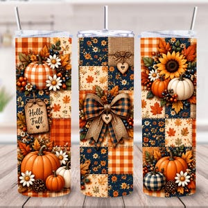 May include: Three cylindrical tumblers with straws featuring a patchwork design of orange and navy blue plaid, autumn leaves, sunflowers, daisies, and pumpkins. One tumbler displays a wooden tag with the text Hello Fall and a small heart.