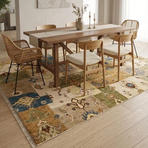 May include: A dining room scene featuring a wooden table with a beige runner, surrounded by wooden chairs and a woven chair. A colorful patchwork rug with floral and geometric patterns covers the floor. A vase with dried flowers and candlesticks are on the table.