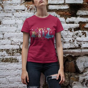 Pu&ograve; includere: Una t-shirt a maniche corte rosso scuro con una stampa grafica di quattro personaggi animali animati e il testo "Anyone can be anything" in carattere corsivo. La maglietta ha un girocollo e un orlo dritto in tessuto a tinta unita.