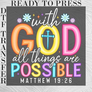 May include: A DTF transfer design with the text "READY TO PRESS". The design features the words "with GOD all things are POSSIBLE" in colorful, stylized lettering, with a cross and floral accents. The Bible verse Matthew 19:26 is also included.