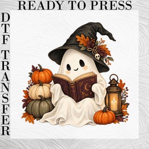 May include: A DTF transfer featuring a white ghost wearing a black witch hat adorned with autumn leaves and a small skull. The ghost reads a brown book with a moon design, surrounded by orange, white, and green pumpkins and a lit lantern.