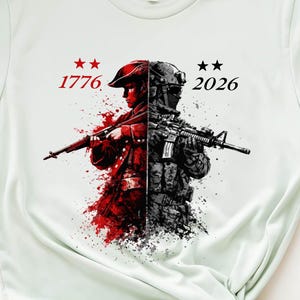 May include: A light green t-shirt featuring a split graphic of a soldier in red and black, holding a rifle. The text "1776" and "2026" with stars are above the soldier. The shirt is knotted at the bottom.