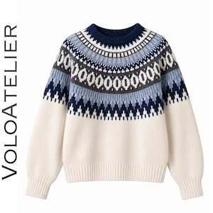 Op de afbeelding: Een crèmekleurige trui met lange mouwen en een donkerblauw, lichtblauw en grijs Fair Isle-patroon rond de halslijn en schouders. De trui heeft een geribbelde ronde hals, boorden en zoom. De tekst VOLOATELIER staat aan de linkerkant afgedrukt.