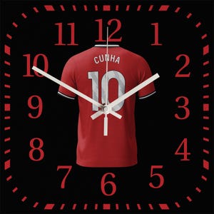Puede incluir: Reloj de pared cuadrado con esfera negra y números rojos. El reloj presenta una camiseta roja con el nombre "CUNHA" y el número "10" en la espalda. Las manecillas blancas indican la hora.
