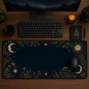 Peut inclure: Un tapis de bureau rectangulaire avec un fond bleu marine fonc&eacute; orn&eacute; d'illustrations c&eacute;lestes dor&eacute;es, incluant un croissant de lune, un soleil avec un visage, des &eacute;toiles et des motifs de feuillage botanique sur les bords.