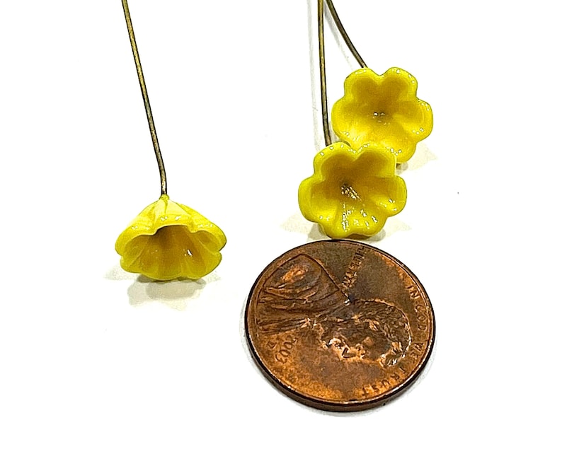 May include: Three yellow flower embellishments with gold wire stems. The flowers are about the size of a UK penny.