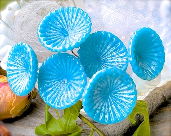 May include: A cluster of six blue glass flower-shaped ornaments with white accents. The ornaments have a textured, rippled surface and are arranged in a bouquet.