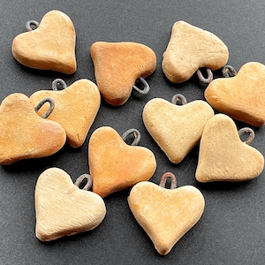 May include: Ten small, heart-shaped wooden ornaments with a rustic brown finish. Each heart has a small metal loop for hanging.