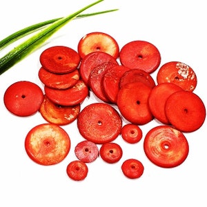 Peut inclure: Un ensemble de perles rondes en corail rouge avec un trou au centre. Les perles sont de différentes tailles et ont une texture naturelle légèrement rugueuse.