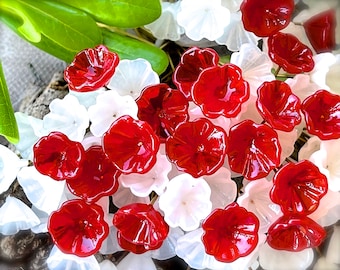 May include: A cluster of red and white glass flowers. The flowers are arranged in a random pattern and have a glossy finish.