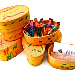May include: A collection of small, handcrafted wooden boxes with lids, painted in shades of yellow and decorated with colorful accents. Some boxes contain miniature dolls made of yarn. The boxes are arranged on a white background.