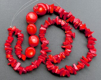 May include: A strand of red coral beads, featuring both round and irregular shaped beads. The beads are strung on a clear cord.