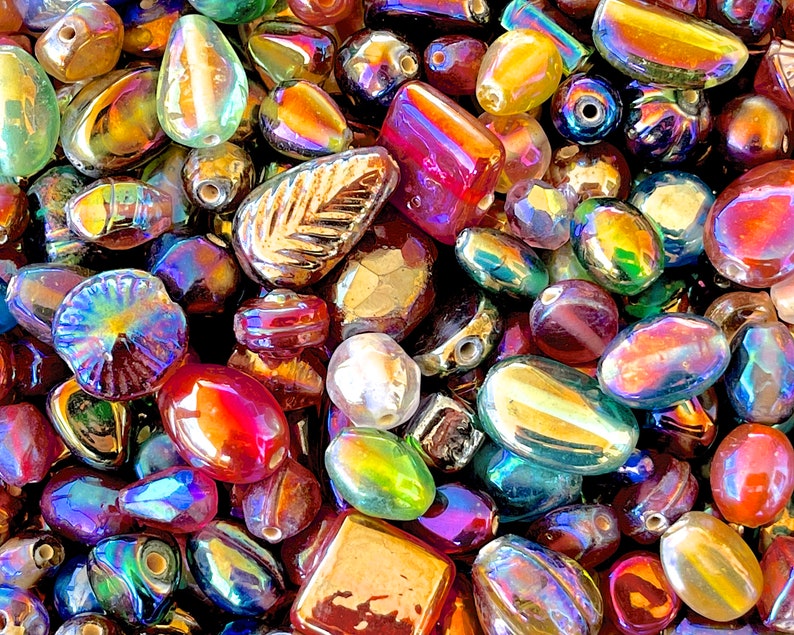 K&ouml;nnte beinhalten: Eine Sammlung von irisierenden Glasperlen in verschiedenen Formen und Gr&ouml;&szlig;en, darunter Tropfen-, Oval- und Rundformen. Die Perlen haben einen regenbogenartigen Glanz und eignen sich perfekt f&uuml;r die Schmuckherstellung oder das Basteln.
