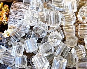 Peut inclure: Un tas de perles en verre transparent avec une forme hexagonale facetée. Les perles ont une texture striée et sont parfaites pour la fabrication de bijoux.