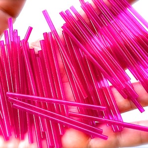 May include: A large pile of bright pink glass rods, perfect for crafting and jewelry making.