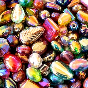 K&ouml;nnte beinhalten: Eine Sammlung von regenbogenfarbenen Glasperlen in verschiedenen Formen und Gr&ouml;&szlig;en, darunter runde, ovale und blattf&ouml;rmige Perlen. Die Perlen haben einen regenbogenartigen Glanz und sind perfekt f&uuml;r die Schmuckherstellung oder das Basteln.