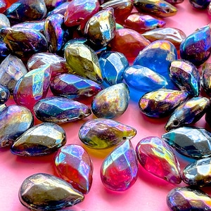 May include: A collection of iridescent teardrop-shaped glass beads in various shades of blue, purple, green, and red. The beads have a faceted design and are perfect for jewelry making.