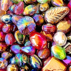 K&ouml;nnte beinhalten: Sortiment aus irisierenden Glasperlen in verschiedenen Formen und Gr&ouml;&szlig;en, darunter runde, ovale und blattartige Perlen. Die Perlen sind in Rot-, Gold-, Gr&uuml;n- und Blaut&ouml;nen.