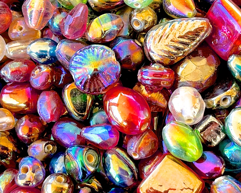 K&ouml;nnte beinhalten: Sortiment aus irisierenden Glasperlen in verschiedenen Formen und Gr&ouml;&szlig;en, darunter runde, ovale und blattartige Perlen. Die Perlen sind in Rot-, Gold-, Gr&uuml;n- und Blaut&ouml;nen.