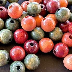 May include: A collection of wooden beads in various colors, including red, orange, and green. Each bead is spherical with a hole drilled through the center. The beads have a natural wood grain texture and a glossy finish, suitable for jewelry making.
