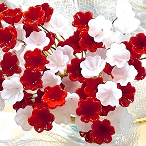 May include: A bouquet of red and white glass flowers. The flowers are arranged in a vase and are displayed on a white background.