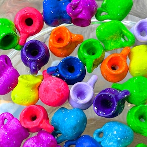 Pode incluir: Uma coleção de jarros em miniatura de cerâmica pintados à mão em vários tamanhos e formas. Os jarros são decorados com cores brilhantes e padrões, incluindo azul, verde, vermelho, amarelo, roxo e branco.