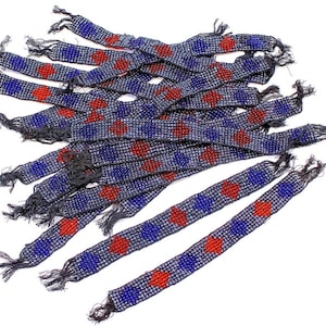 May include: A pile of beaded bracelets with a blue and red geometric pattern. The bracelets are made of small, round beads and have a fringe at the ends.