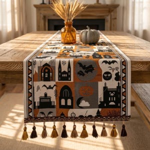 May include: A rectangular table runner featuring a repeating pattern of black and orange Halloween motifs including haunted houses, bats, pumpkins, and moons. The runner has a decorative border with geometric triangles and brown fringe tassels.