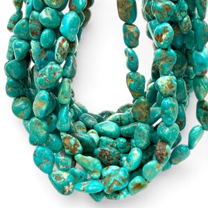 May include: A multi-strand necklace composed of numerous polished, irregular turquoise nuggets. Each stone features a vibrant cyan-blue color with distinct brown matrix veining, creating a textured, organic appearance throughout the layered strands.