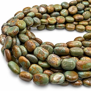 May include: A strand of smooth, oval-shaped beads featuring a marbled pattern of earthy green, brown, and tan tones. Each bead has a polished, glossy finish with unique natural color variations, arranged in a curved, dense formation.