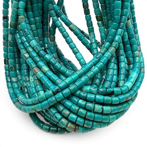 May include: Close-up of multiple strands of turquoise-colored, square-shaped beads. The beads are strung together, forming a cascading arrangement. The turquoise color is vibrant, with variations in tone. The beads appear to be made of a natural stone material.