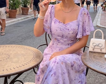 Lavendelkleurige maxi-jurk met bloemenprint, vlinderprint, ruchesmouwen en sweetheart-halslijn, perfect voor een zomerse bruiloft, tuinfeest of andere gelegenheid in cottagecore-stijl.